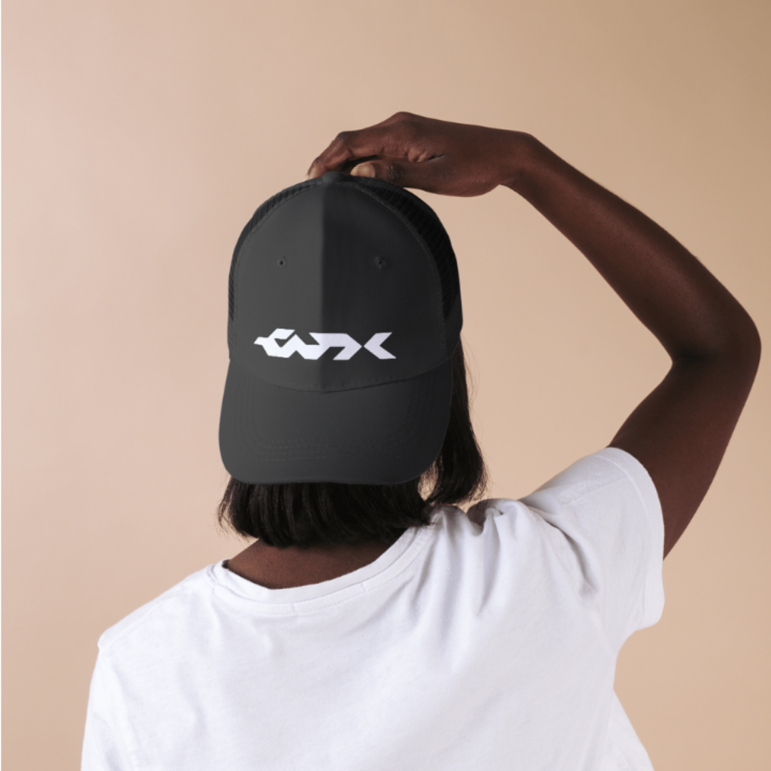 Person wearing a black cap with a white logo on a beige background