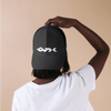 Person wearing a black cap with a white logo on a beige background
