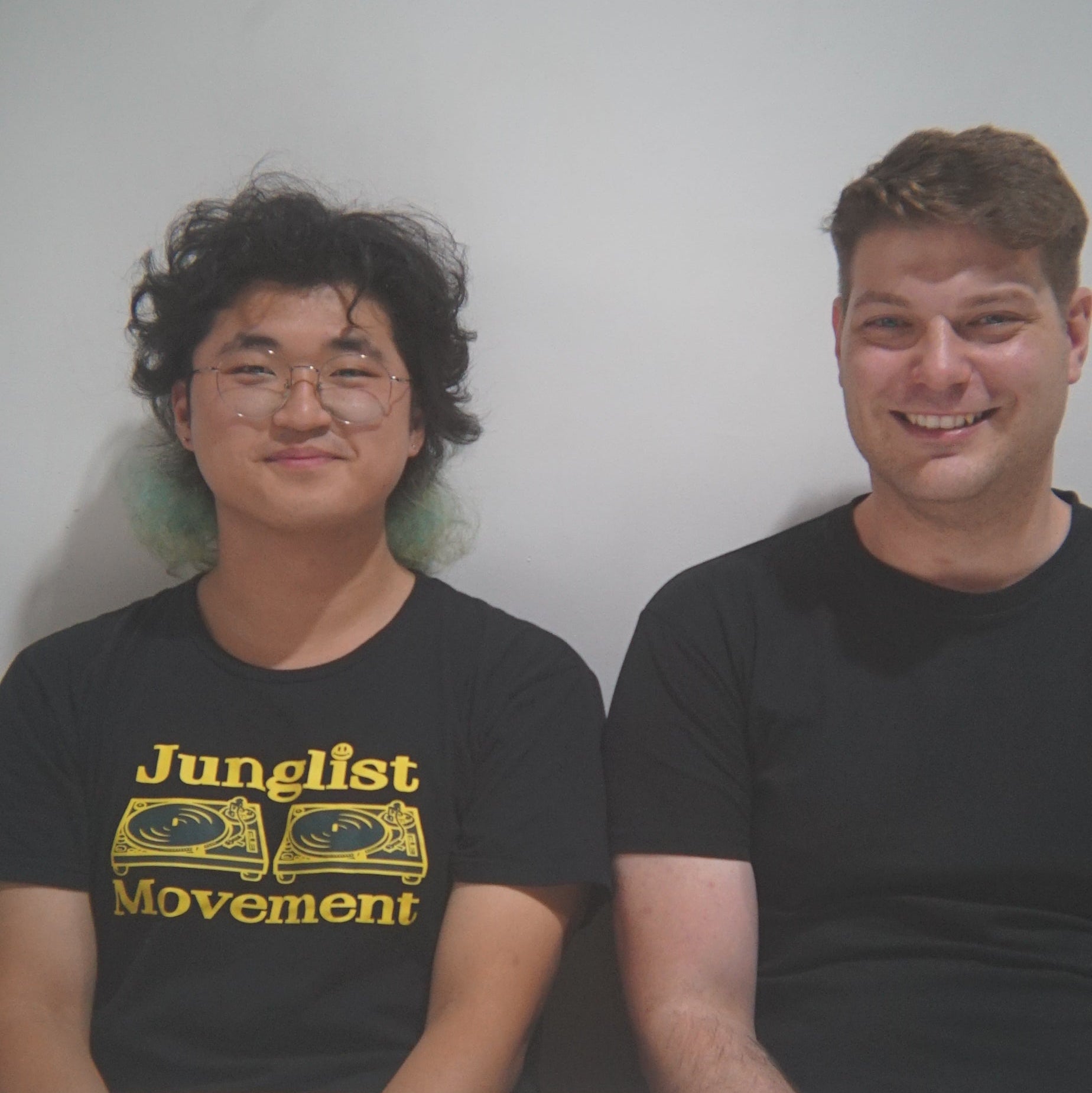 Two people wearing black t-shirts with yellow text against a white background
